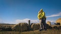 Man and woman in yellow green sportswear. Lovely couple of travelers hug and kiss near old stone enjoying highland Royalty Free Stock Photo