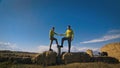 Man and woman in yellow green sportswear. Lovely couple of travelers hug and kiss near old stone enjoying highland Royalty Free Stock Photo