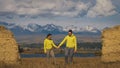 Man and woman in yellow green sportswear. Lovely couple of travelers hug and kiss near old stone enjoying highland Royalty Free Stock Photo