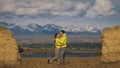 Man and woman in yellow green sportswear. Lovely couple of travelers hug and kiss near old stone enjoying highland Royalty Free Stock Photo