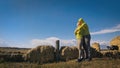 Man and woman in yellow green sportswear. Lovely couple of travelers hug and kiss near old stone enjoying highland Royalty Free Stock Photo