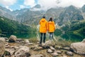 man with woman in yellow raincoat at sunny autumn day looking at lake in tatra mountains Royalty Free Stock Photo
