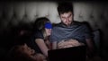 Man and woman, young couple watching boring movie on laptop in bed before bedtime Royalty Free Stock Photo