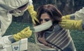 People in bacteriological protective suits putting a mask on woman