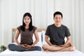 Man and woman Buddhist sitting on bed in the bedroom and doing meditation in Buddhism religion style together. The idea for faith Royalty Free Stock Photo