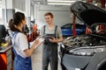 Man and woman car mechanic talking discussing causes of car failure Royalty Free Stock Photo