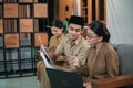 man and women civil servants holding and looking paperwork when sitting while working online