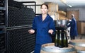 man and women coworkers looking at bubbly wine in bottle standing in wine cellar