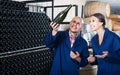 man and women coworkers looking at bubbly wine in bottle standing in wine cellar