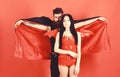 Man and woman dressed like vampire, demon, red background. Vampire in cloak behind sexy devil girl. Couple in love Royalty Free Stock Photo