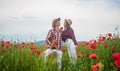 Man and woman embracing and kissing in poppy field on the dusk with guitar, music Royalty Free Stock Photo