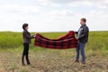 Man and woman lay a blanket on the ground for a picnic in nature Royalty Free Stock Photo