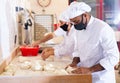 Man and woman in protective mask prepare bread in the kitchen of bakery Royalty Free Stock Photo