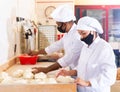 Man and woman in protective mask prepare bread in the kitchen of bakery Royalty Free Stock Photo