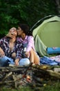 Man and woman relaxing near firebone and camping tent. Travel, love and living in nature concept. Sensual young couple