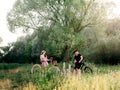 Man and woman resting on bicycles at summer nature. Coutryside or park with greenery