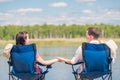 Man and woman are sitting on chairs at the pier near the lake an Royalty Free Stock Photo