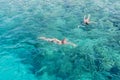 Man and women snorkeling in tropical water on vacation. Woman swimming in blue sea. Snorkeling girl in full-face snorkeling mask.