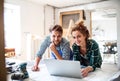 Young couple with laptop in the carpenter workroom.