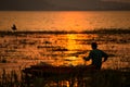 Man in wood fishing boat in the water and sunset, sunrise Royalty Free Stock Photo