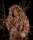 Man in a wood goblin costume, holding a withered trees