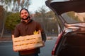 Man with wooden box of yellow ripe golden apples at the orchard farm loads it to his car trunk. Grower harvesting in the Royalty Free Stock Photo