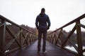 Man on wooden bridge over a lake, on a damp autumn day.