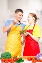 a man with a wooden spoon and a girl with a bowl of salad try the food cooked together