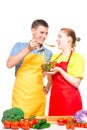 a man with a wooden spoon and a girl with a bowl of salad try the food cooked together on a white