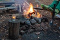 Man in the woods by the fire warms his feet in woolen socks, cropped photo, Camping concept, grill Royalty Free Stock Photo