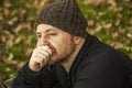 Man with wool hat sitting on the bench in the park in autumn background.Extreme close up portrait pensive man with wool hat Royalty Free Stock Photo