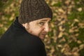 Man with wool hat sitting on the bench in the park in autumn background..Extreme close up rear view portrait pensive man with woo Royalty Free Stock Photo