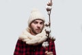 Man in a woolen scarf and hat is holding a cotton branch on grey background Royalty Free Stock Photo