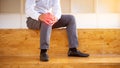 A man in work clothes has knee pain and is seated i Royalty Free Stock Photo