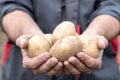 A man in work clothes holding potatoes on his outstretched hands