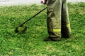 Man in work clothes mows green grass with a trimmer Royalty Free Stock Photo