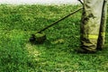 Man in work clothes mows green grass with a trimmer Royalty Free Stock Photo