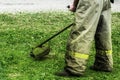 Man in work clothes mows green grass with a trimmer Royalty Free Stock Photo