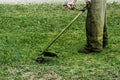 Man in work clothes mows green grass with a trimmer Royalty Free Stock Photo