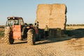 a man in work clothes preparing feed to be transported on a tractor