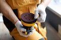 Man in work gloves holds tool sander machine