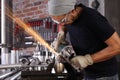 Man work in home workshop garage with angle grinder, goggles and construction gloves, sanding metal makes sparks closeup, diy and Royalty Free Stock Photo