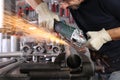 Man work in home workshop garage with angle grinder, goggles and construction gloves, sanding metal makes sparks closeup, diy and Royalty Free Stock Photo
