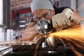 Man work in home workshop garage with angle grinder, goggles and construction gloves, sanding metal makes sparks closeup, diy and Royalty Free Stock Photo