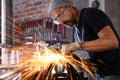 Man work in home workshop garage with angle grinder, goggles and construction gloves, sanding metal makes sparks closeup, diy and Royalty Free Stock Photo