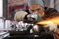 Man work in home workshop garage with angle grinder, goggles and construction gloves, sanding metal makes sparks closeup, diy and Royalty Free Stock Photo