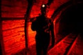 A man in work overalls and a helmet with a jackhammer on his shoulder is standing on the rails. Silhouette in red. Miner