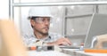 Man work, professional construction worker with computer, plastering tools on scaffolding, safety hard hat, gloves and protective