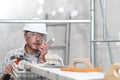 Man work, professional construction worker  with mobile cell phone, plastering tools on scaffolding, safety hard hat, gloves and Royalty Free Stock Photo