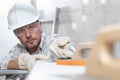 Man work, professional construction worker with plastering tools on scaffolding, safety hard hat, gloves and protective glasses.